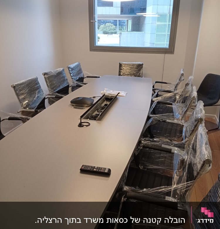 שולחן ישיבות עם כיסאות עטופים בניילון וחלון גדול